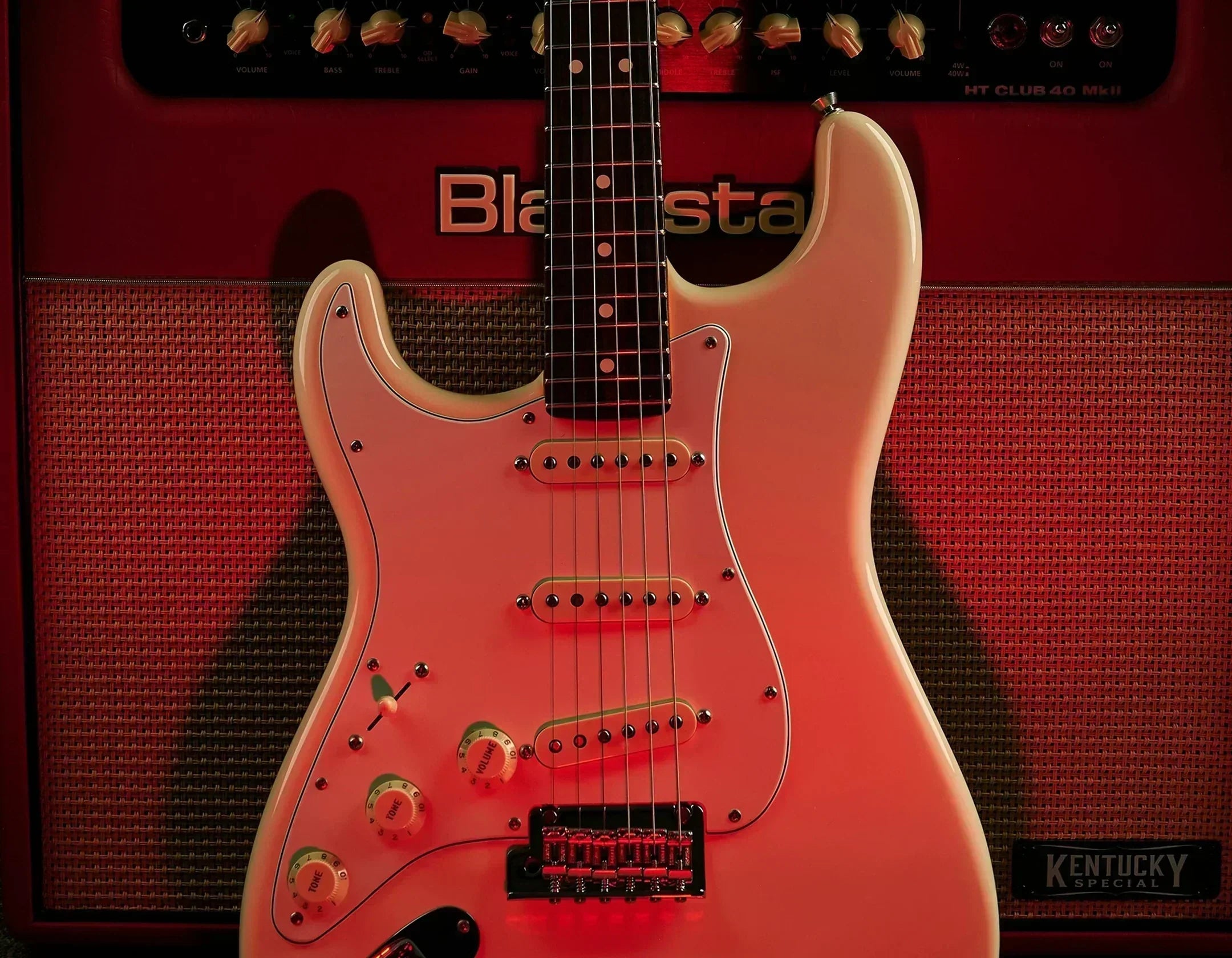 Fender Stratocaster leaning on red amp with red glow.