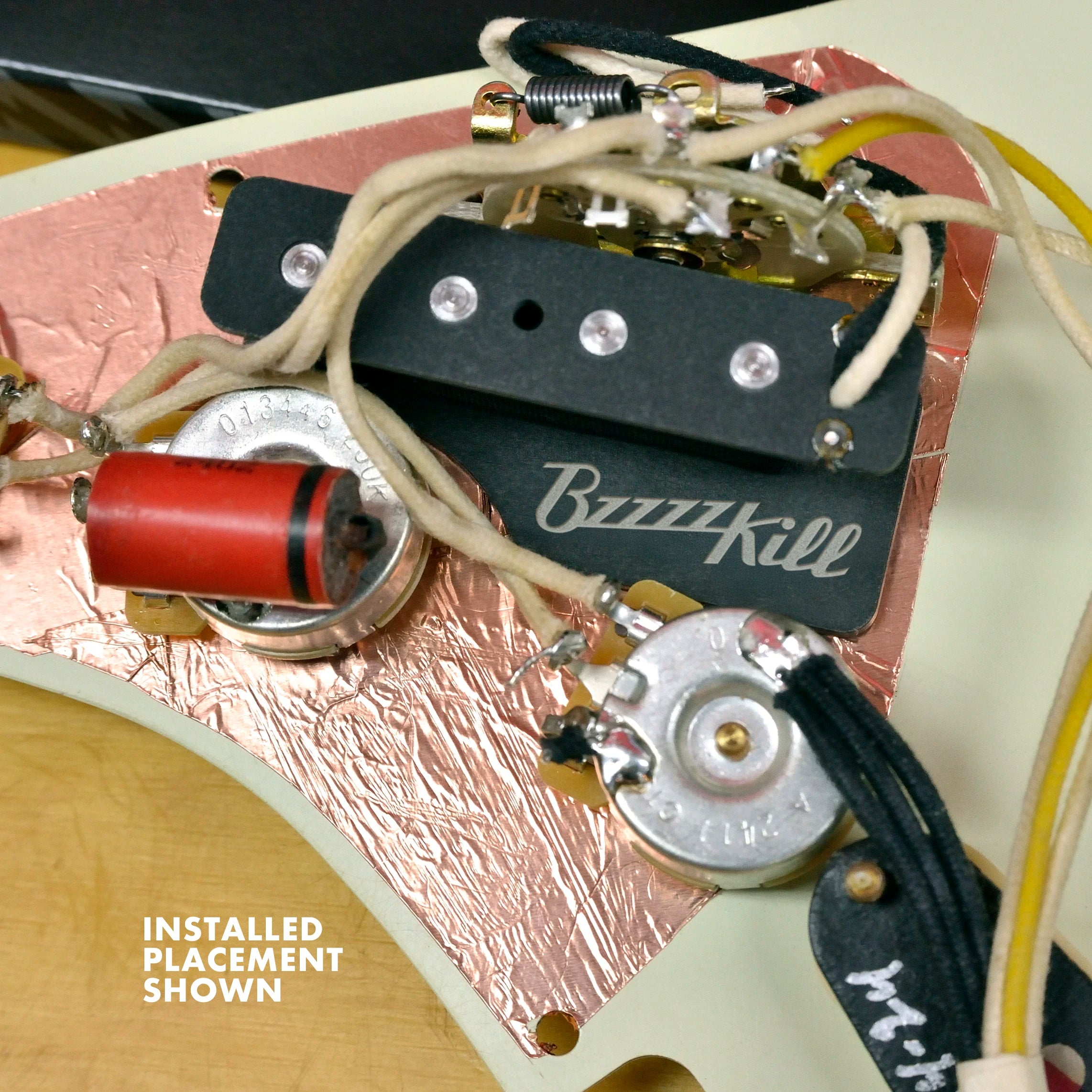 Underside of pickguard showing where BzzzzKill device is installed and wired inside a Stratocaster guitar.