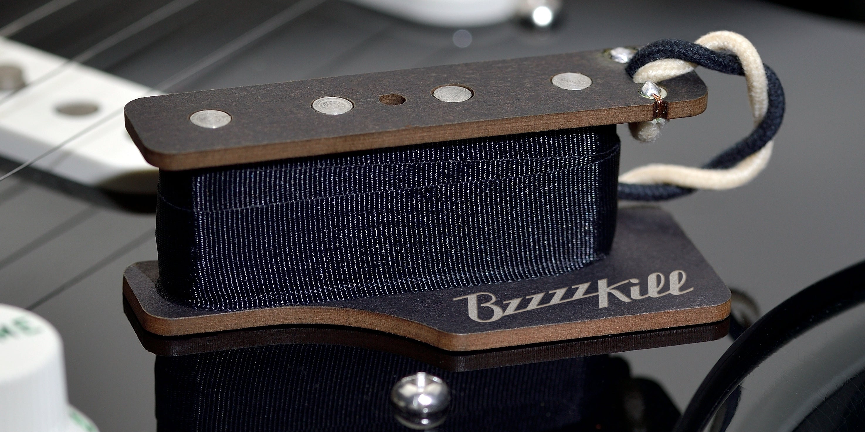 The BzzzzKill Single Layer device for eliminating Fender Stratocaster 60 cycle hum in all pickup selector positions. Sitting on black Stratocaster.
